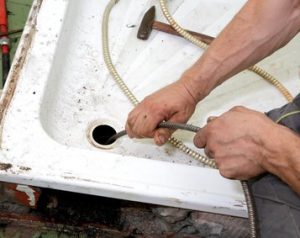 Plumber cleaning  drain in bathroom with cable